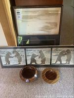 View of three framed art prints and two wooden bowls on the floor illustrating lot contents