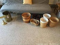 Photo showing a variety of baskets including wooden, woven, ceramic, and crochet style on carpeted floor with sofa background.