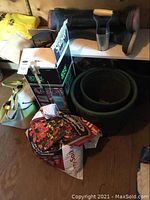 Overview of gardening bag, soil bags, pots stacked, boots on shelf