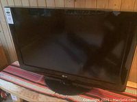 Front view of LG 32 inch television showing screen and surrounding frame on a wooden surface.