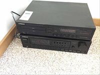 Image showing the stacked Pioneer PD-T303 CD player on top of the Pioneer SX-1300 stereo receiver, both with black casing and front controls, placed on carpeted floor.