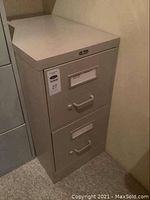 Front view of beige two-drawer metal file cabinet with handles and label holders on each drawer.