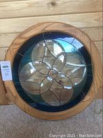 Front view of the circular stained glass panel showing entire floral design in glass and wooden frame.