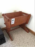 Full front view of vintage solid wood magazine rack against wall on carpet, showing side handle cutouts and pegged joinery.
