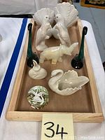 Overall group of ceramic and decorative figurines and trinkets on wooden tray including peacocks, tall green bird figurines, elephant, swan trinket box, small bird, and round box