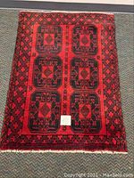 Full view of the red and black prayer rug with six main black octagonal panels containing floral motifs on red field, showing the overall pattern and fringe edges.