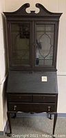 Front view of the antique drop front secretary desk with glass doored bookcase on top, drop front closed, two drawers at the bottom.
