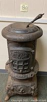 Full view of the antique cast iron wood stove showing the top, front door with embossed model and number, and ornate base.