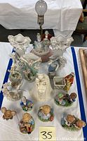 Overhead view of multiple porcelain figurines including children, animals, and a pair of floral vases.
