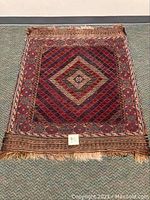 Full view of flat weave village rug showing diamond pattern and fringe.