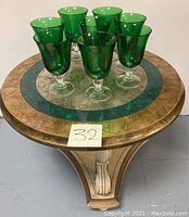 Top view of round coffee table showing inlay and eight emerald green glasses arranged on top.