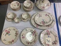 Full view of various china pieces including soup cups, saucers, creamer, dessert bowls, casserole dish with lid, platters, and plates arranged on a table.