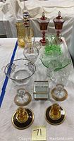 Full lot of mid-century art glass items including candlesticks, lidded jars, pitchers, Galileo thermometer, vanity box and decorative plates arranged on table.