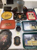 Overview of all tinware items on display: various decorated tole trays, metal water can, spice caddy, and small containers.