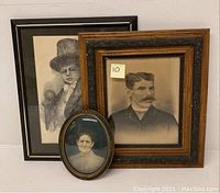 Three framed old portrait prints including an oval print of a woman, a wood-framed male portrait print, and a black framed grayscale sketch of a boy.