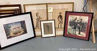 Five framed old portrait prints including a house scene and historical figures arranged on a table