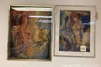 Two framed pastel portraits hanging on a wall depicting nude women in artistic contexts with multiple figures.
