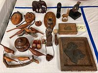 Overall view of the full lot of wooden figurines and carved items on a white cloth.