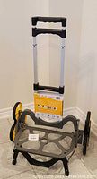 Full shot showing UpCart hand truck folded with handle up and stair climbing wheel assemblies in view.