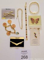 Image showing the full lot of costume jewellery including bracelets and brooches on a white background with a MaxSold tag.