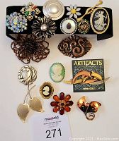Top view of the full set of 14 vintage costume jewelry brooches laid on black display.