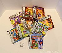 Photo showing ten different empty Game Boy Advance game boxes spread out on a white surface.