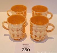 Four vintage Fire King glass mugs with textured diamond pattern viewed from the front on a white background