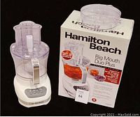 Food processor assembled with the larger 12-cup bowl and lid, placed next to the original box showing the product name and image.