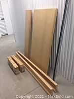 Separated flat wooden panels, long slats, and hardware for the Ikea Malm double bed with light wood finish.