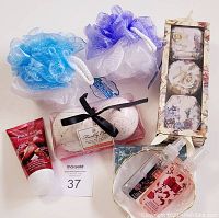 Two mesh bath loofahs (blue and purple), Upper Canada bath bombs in clear box with black ribbon, pomegranate hand cream, and two scented sprays.