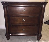 Front view of single nightstand showing three drawers and metal knobs