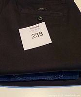 Black Denver Hayes pants folded showing back pocket button and fabric detail