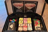 Open box showing organized play money, cards, and tokens inside black plastic tray.