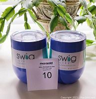 Two blue Swig Life stemless cups with lids and label showing brand and insulation features.