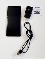 Front view of phone face down with charger and cable