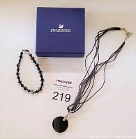 Photo of Swarovski box alongside black crystal necklace and bracelet on white background.