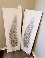 Both feather oil paintings shown leaned against wall side by side, illustrating size and condition