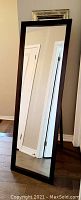 Front view of the full-length mirror showing dark wooden frame and reflective surface.