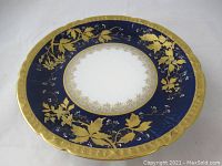 Top view showing ornate cobalt blue and gold gilt floral pattern on scalloped rim porcelain plate