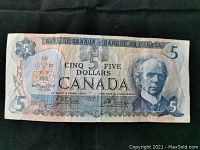 Front view of a 1979 Canadian five dollar bill showing the portrait of Sir Wilfrid Laurier, Canadian coat of arms, and denomination markings in English and French.