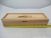 Closed wooden box with Native Essence logo, measuring about 11 inches in width, used to store the ladle.