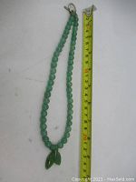 Full necklace laid out beside a measuring tape showing approximately 20 cm length of beads.