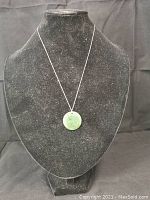 Jade pendant on a black necklace bust showing the full front view of the pendant and chain.