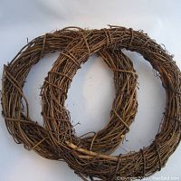 Two round intertwined wicker wreaths placed overlapping on a white background showing their full shape and condition.