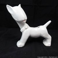 Side view of vintage ceramic cat figurine showing smooth white finish with minimal detail and a bow at the neck.