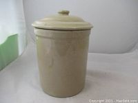 Full view of vintage beige ceramic pickling crock with lid on.