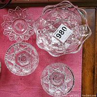 Top view showing four crystal candy dishes on a pink cloth, displaying intricate cut glass patterns and shapes