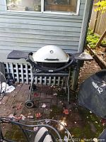 Front view of the Weber portable BBQ grill on stand showing white dome lid, side shelves, and wheels.