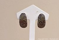 Close-up of earrings showing multi-colour crystals ranging from clear to amber on a curved base with 14K posts.