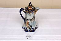 Full view of the Kutani coffee/tea pot showing its hand-painted design, blue handle, and the overall shape with spout and lid.